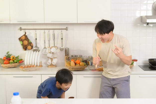Feliz jovem asiático pai e filho fazendo café da manhã juntos brincalhão na cozinha em casa