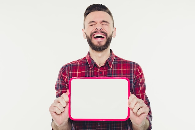 Foto feliz jovem barbudo mostrando e exibindo cartaz vazio branco pronto para seu texto ou produto ou anúncio