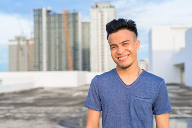 Feliz, jovem, bonito, multi, étnico, homem, sorrindo, contra, vista cidade