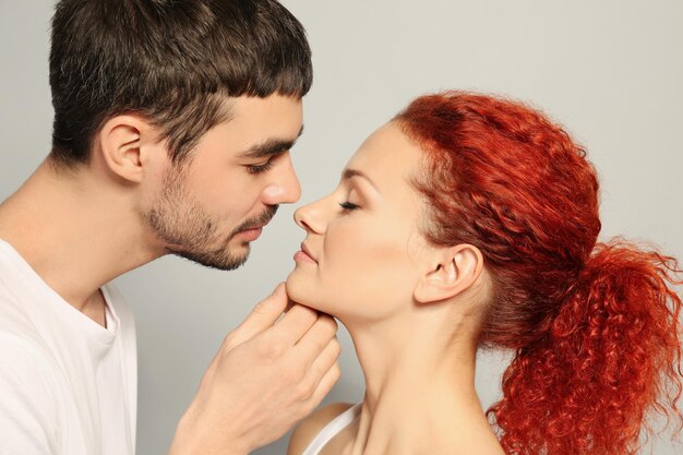 Feliz jovem casal apaixonado beijando em fundo cinza close-up