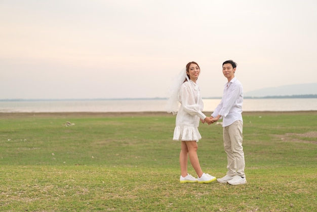 Feliz jovem casal asiático em roupas de noivos