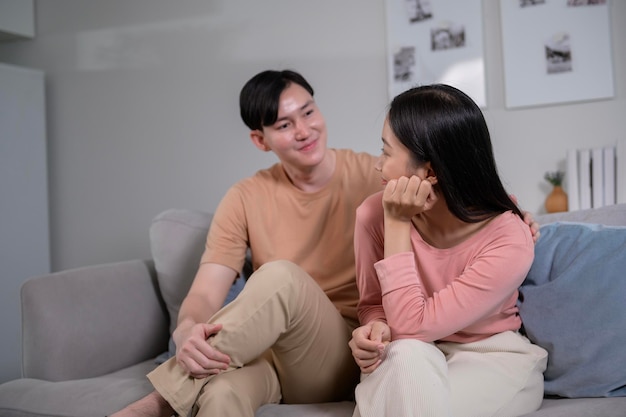 Feliz jovem casal asiático sentado no sofá relaxando juntos na sala de estar em casa