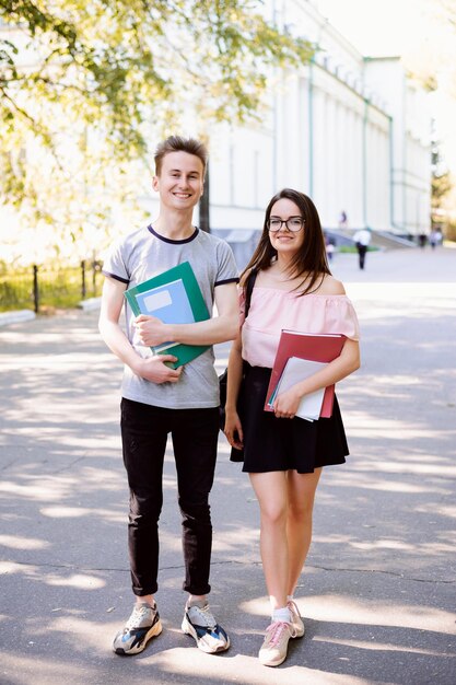 Feliz jovem casal de estudantes perto da universidade convencional