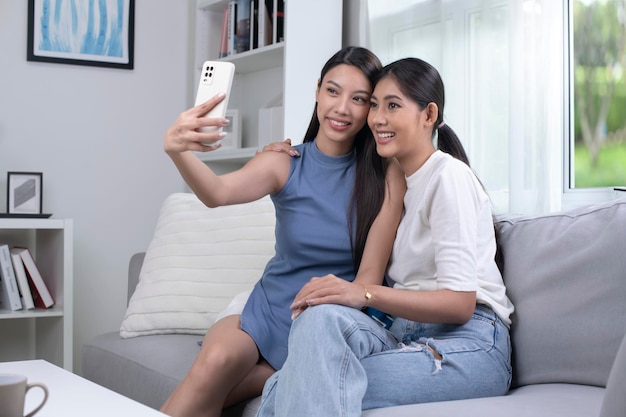 Feliz jovem casal de lésbicas asiáticos tirando selfie na sala de estar conceito de estilo de vida do casal LGBT