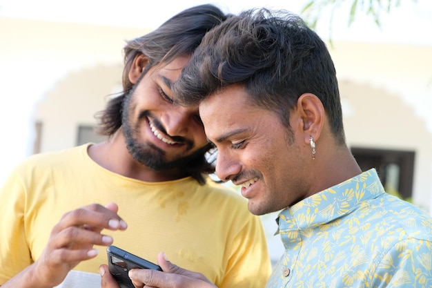 Feliz jovem casal gay indiano olhando suas fotos no telefone ao ar livre