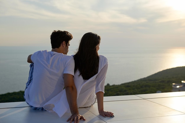 feliz jovem casal romântico divirta-se relaxe sorria na varanda do terraço ao ar livre em casa moderna