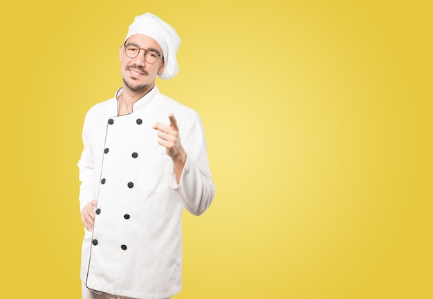 Feliz jovem chef apontando para você com o dedo