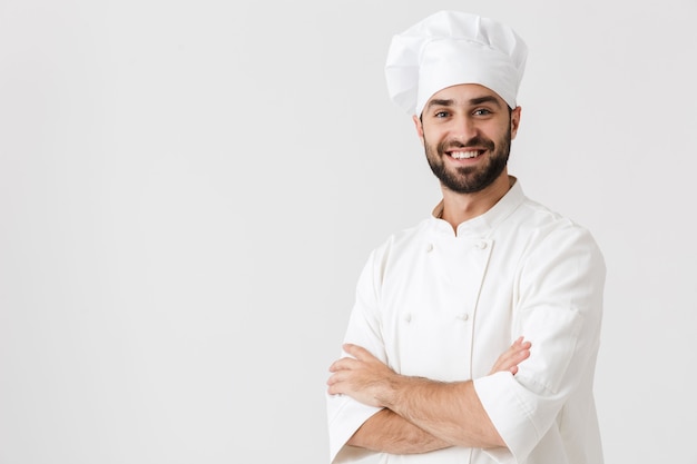 Feliz jovem chef posando de uniforme.