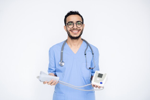 Feliz jovem clínico de sucesso com um sorriso cheio de dentes segurando o tonômetro enquanto fica isolado