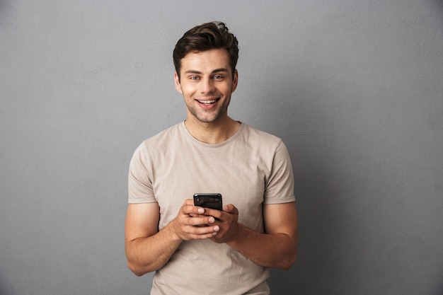 Feliz jovem com cabelo escuro curto, segurando o smartphone e conversando