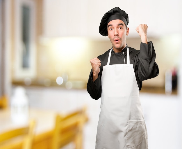 Feliz jovem cozinheiro com um gesto de celebração