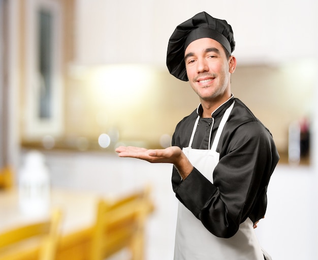 Feliz jovem cozinheiro com um gesto de espera