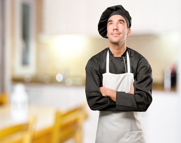 Foto feliz jovem cozinheiro olhando para cima