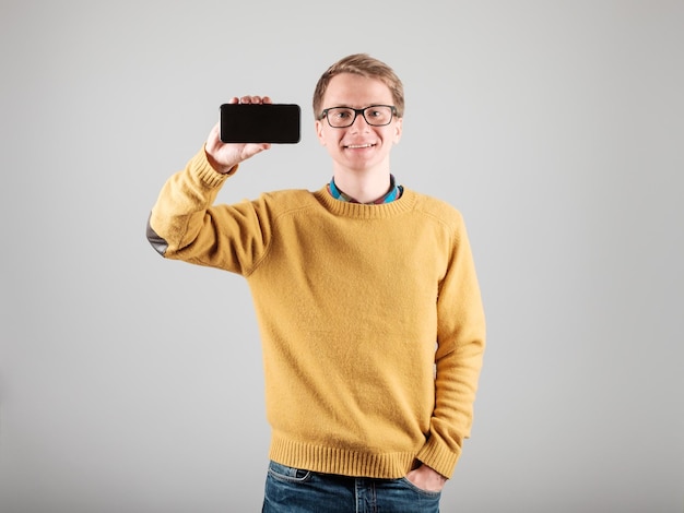 Feliz jovem da moda mostrando a tela em branco do espaço do smartphone do celular para o seu texto