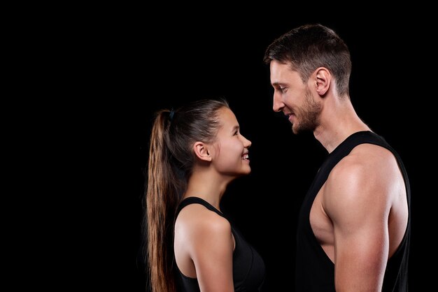 Feliz jovem desportista e desportista de roupa desportiva a olhar um para o outro com sorrisos