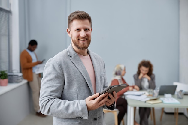 Feliz jovem diretor executivo em elegante terno cinza segurando o tablet