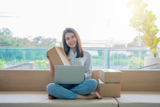 Foto feliz jovem empresária asiática segurar pacote e sorriso para venda sucesso de on-line