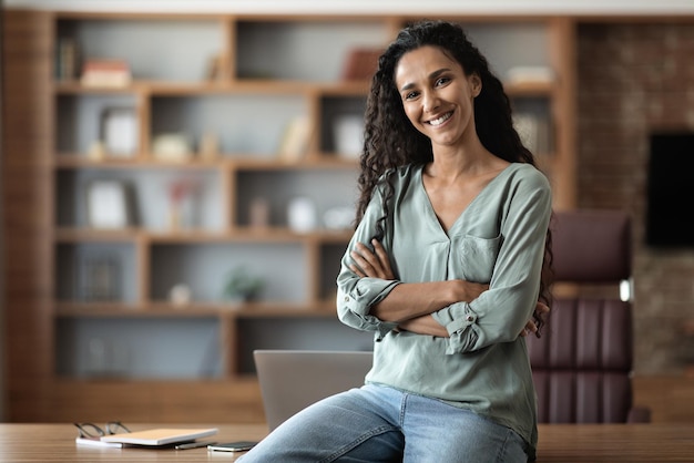 Feliz jovem empresária posando no escritório sorrindo para a câmera