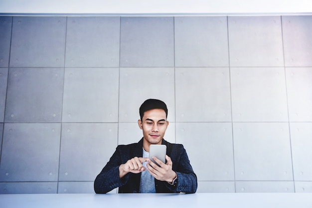 Feliz jovem empresário asiático trabalhando em Smartphone.