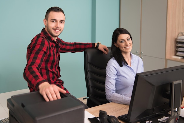 Feliz jovem empresário e mulher trabalham no escritório moderno no computador