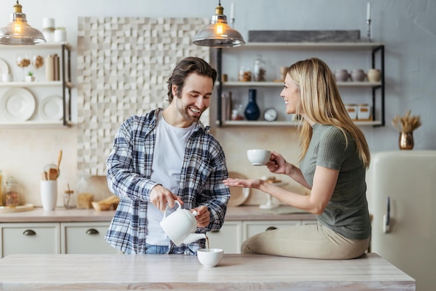 Feliz jovem esposa e marido europeus com restolho bebem chá quente e conversam no tempo livre no moderno