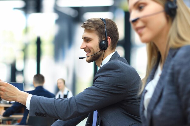 Feliz jovem executivo de suporte ao cliente masculino trabalhando no escritório