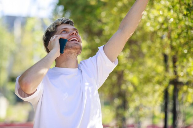 Feliz jovem falando ao telefone e levantou o punho foto de alta qualidade