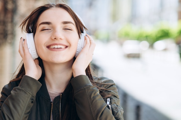 Foto feliz, jovem garota gosta da música que vem dos fones de ouvido.