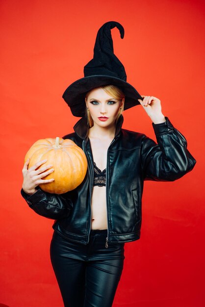 Foto feliz jovem gótica em fantasia de bruxa de halloween bruxa posando com conceito de abóbora de halloween