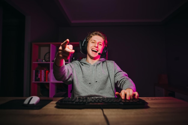 Foto feliz jovem jogador masculino em fone de ouvido e casual faz streaming de jogo