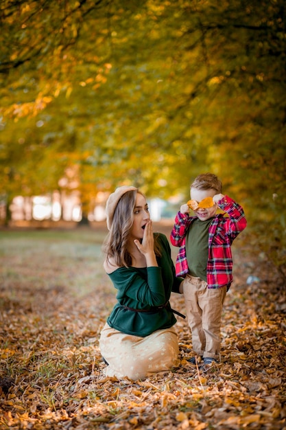 Feliz jovem mãe brincando e se divertindo com seu filho bebê no sol quente do outono no parque Conceito de família feliz