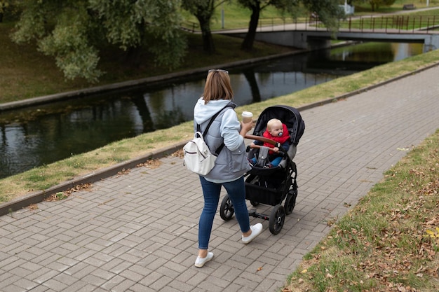 Feliz jovem mãe caminhando com seu filho pequeno no parque