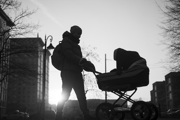 Feliz jovem mãe com carrinho de bebê durante a caminhada na natureza no parque