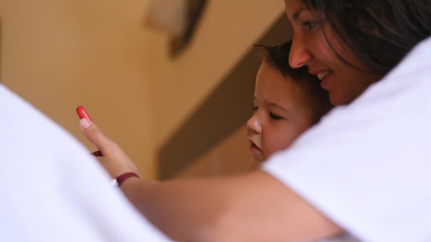 Feliz jovem mãe com filho pequeno usando telefone inteligente juntos Foto de alta qualidade