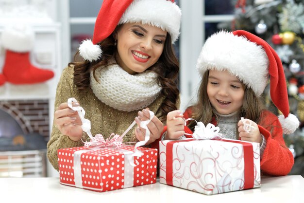 Feliz jovem mãe e filha com presentes de Natal