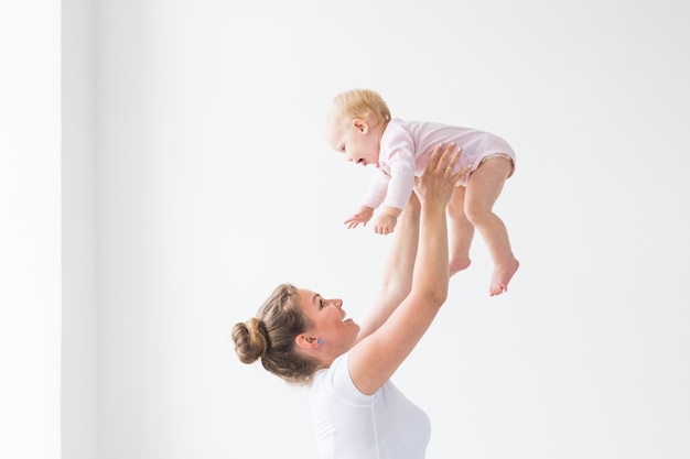 Feliz jovem mãe levantando bebê fofo bem alto, passando e curtindo o tempo junto com a filha.