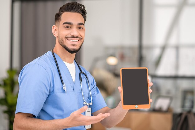 Feliz jovem médico mostrando seu tablet