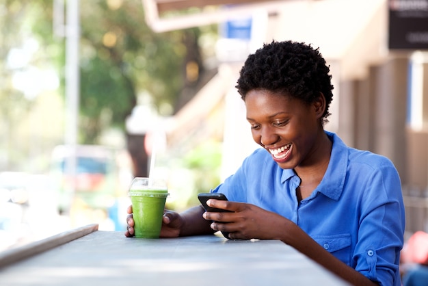 Feliz, jovem, mulher africana, sentando, em, café ao ar livre, usando, telefone móvel