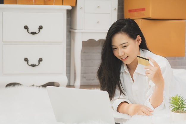 Feliz jovem mulher asiática fazendo compras on-line em casa