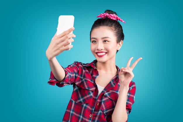 Foto feliz jovem mulher asiática usando smartphone em cima de azul.