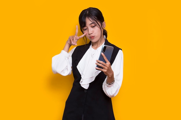 feliz jovem mulher bonita asiática usando telefone celular isolado em fundo amarelo