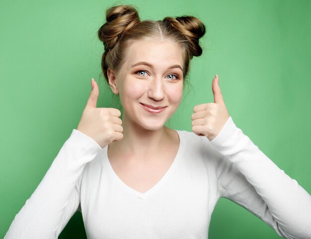 Feliz jovem mulher caucasiana fazendo sinal de polegar para cima e sorrindo alegremente