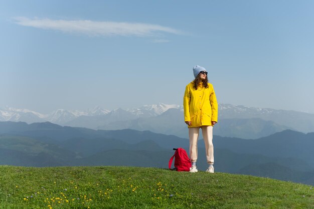 Feliz jovem mulher de pé no topo da montanha contra a cordilheira mulher de sucesso descontraindo nas montanhas