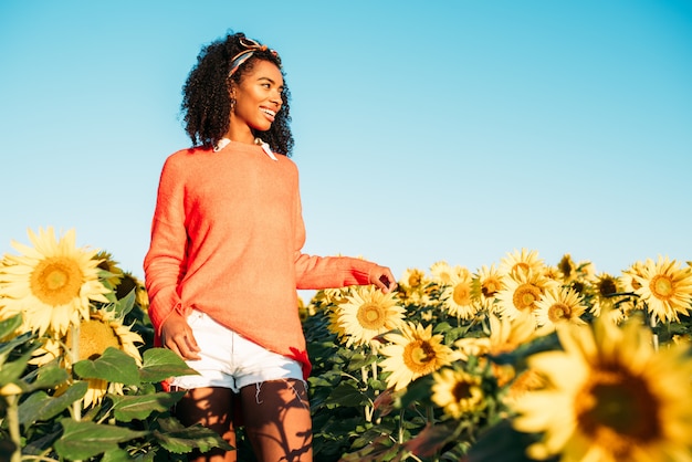 Foto feliz jovem negra andando em um campo de girassol