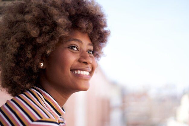 Feliz jovem negra com cabelo afro sorrindo alegre garota afro-americana olhando ao ar livre