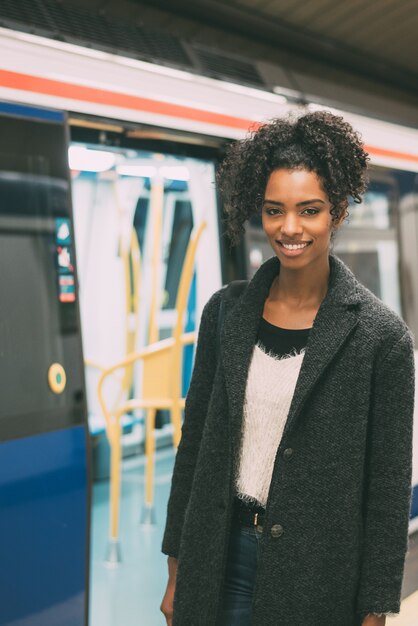 Feliz jovem negra dentro da estação de metro, esperando o trem