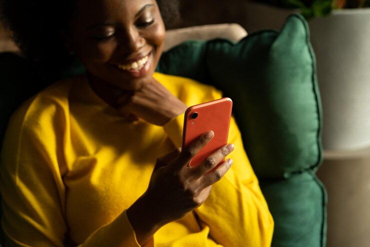 Feliz jovem negra do milênio usando celular digitando mensagem conversando nas redes sociais