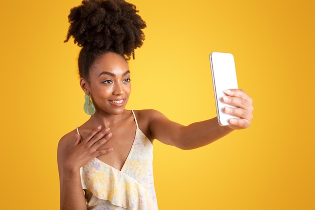 Feliz jovem negra tirando selfie em smartphone usando aplicativo de mídia social