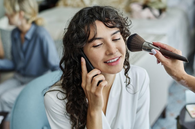 Feliz jovem noiva com cabelo escuro e ondulado, falando no smartphone