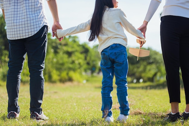 Feliz jovem pai de família asiática, mãe e filha se divertindo e curtindo caminhadas ao ar livre pela estrada juntos no parque natural verde em um dia ensolarado de verão